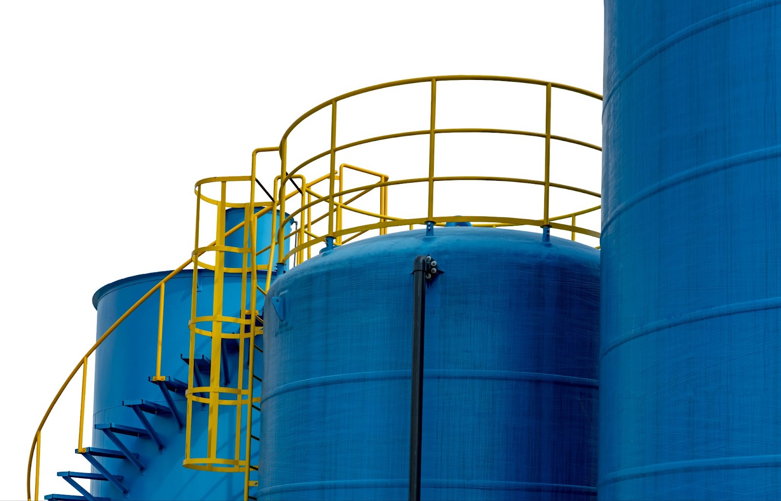 Large blue industrial storage tanks with yellow access stairs, representing chemical storage facilities.
